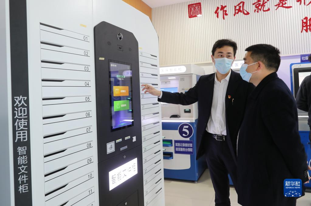 上海市閔行區(qū)七寶鎮(zhèn)社區(qū)事務受理服務中心的工作人員（左）向前來辦事的居民介紹智能文件柜的使用方法（2021年3月3日攝）。
